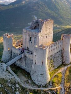 Veduta aerea della meravigliosa Rocca di Calascio il cui fascino è stato fonte d'ispirazione per registi del calibro di Anton Corbijn, in The American con George Cloney, e Richard Donner che l' ha fortemente voluta per le riprese di Ladyhawke. Memorabile la scena in cui Michelle Pfeiffer, nel ruolo di Isabeau D'Anjou, precipita nel vuoto per poi trasformarsi in falco con le prime luci dell'alba. In molti ci identificano il borgo de Il nome della rosa anche se Umberto Eco ha dichiarato che la location delle riprese fu costruita per l'occasione con tecnologie tipiche degli studios cinematografici.